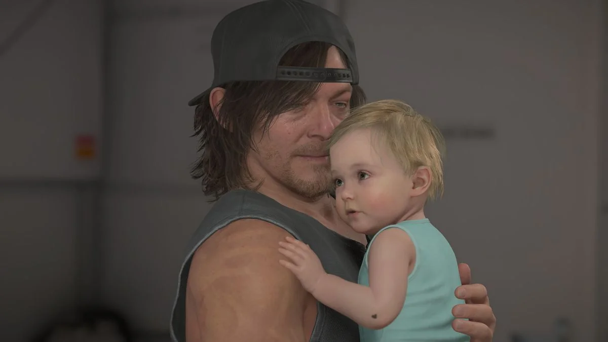 death-stranding-2-erste-eindrucke-und-rezensionen_img_4 | etalongame.de Death Stranding 2 Geburtstag DOOMS: Sam blickt auf Lou, während er sie an seine Brust hält.