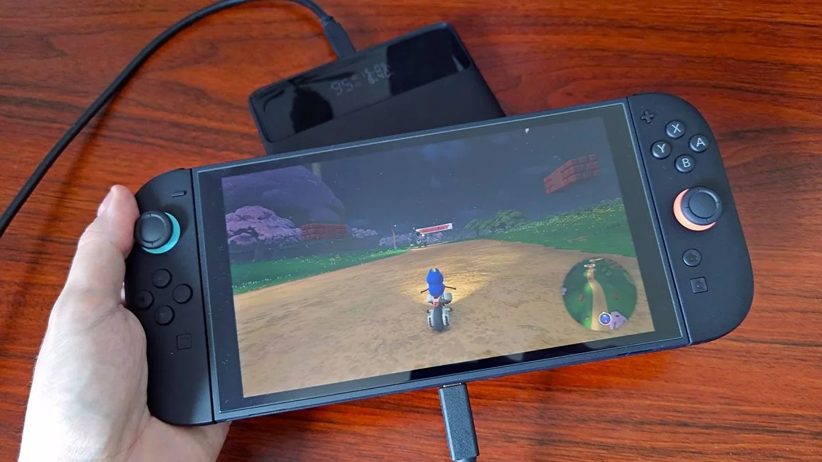 nintendo-switch-2-verlangerte-spielzeit-mit-der-baseus-blade-powerbank_img_0 | etalongame.de Hand hält Switch 2 mit Mario Kart World Gameplay auf dem Bildschirm, während die Baseus Blade Powerbank das Handheld lädt.